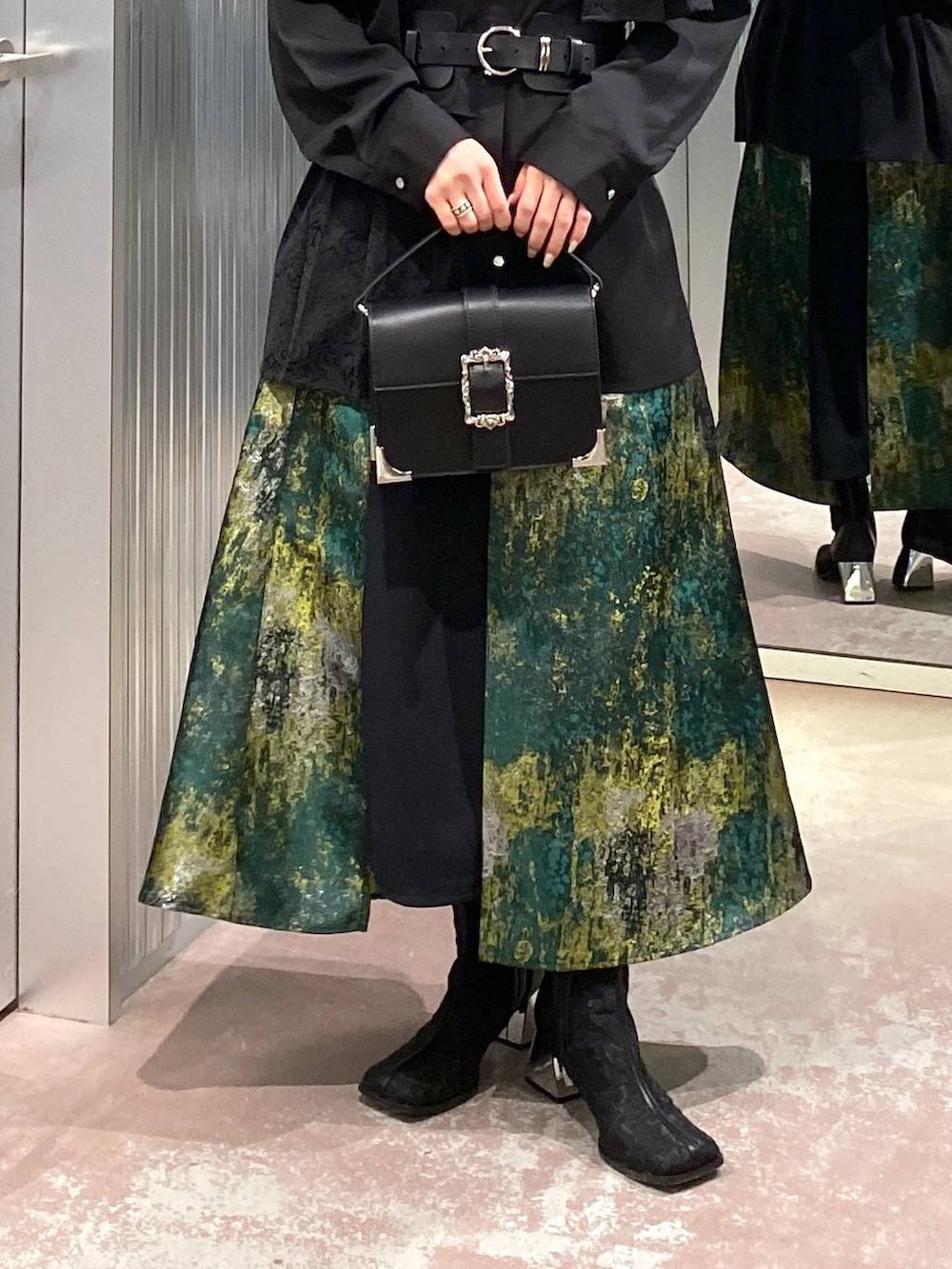 ブラック系のブーツ、イエロー系のスカート、ブラック系のショルダーバッグを着用したレディースの冬コーディネートの8枚目の写真