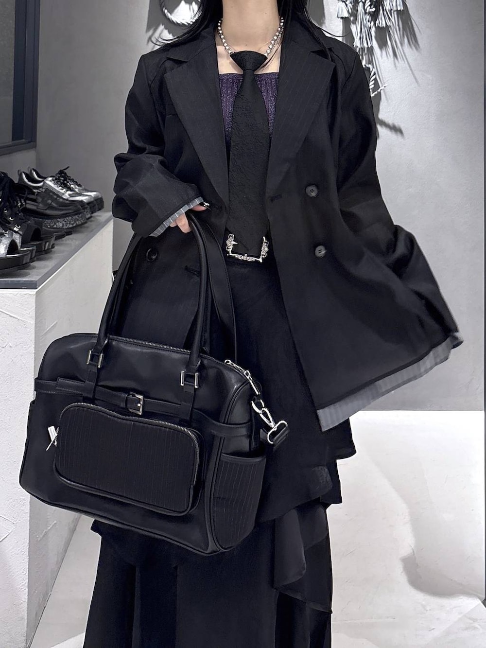 ブラック系のネクタイ、ブラック系のブーツ、パープル系のタンクトップを着用したレディースの春コーディネートの6枚目の写真