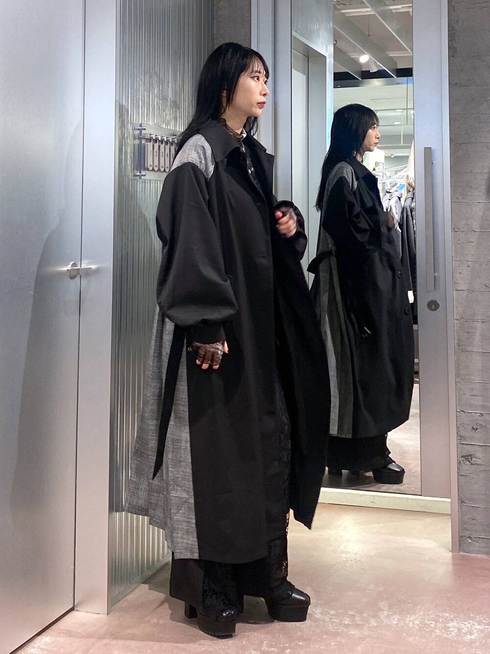 ブラック系のブーツ、ブラック系のステンカラーコート、ブラック系のTシャツ/カットソーを着用したレディースの秋コーディネートの3枚目の写真