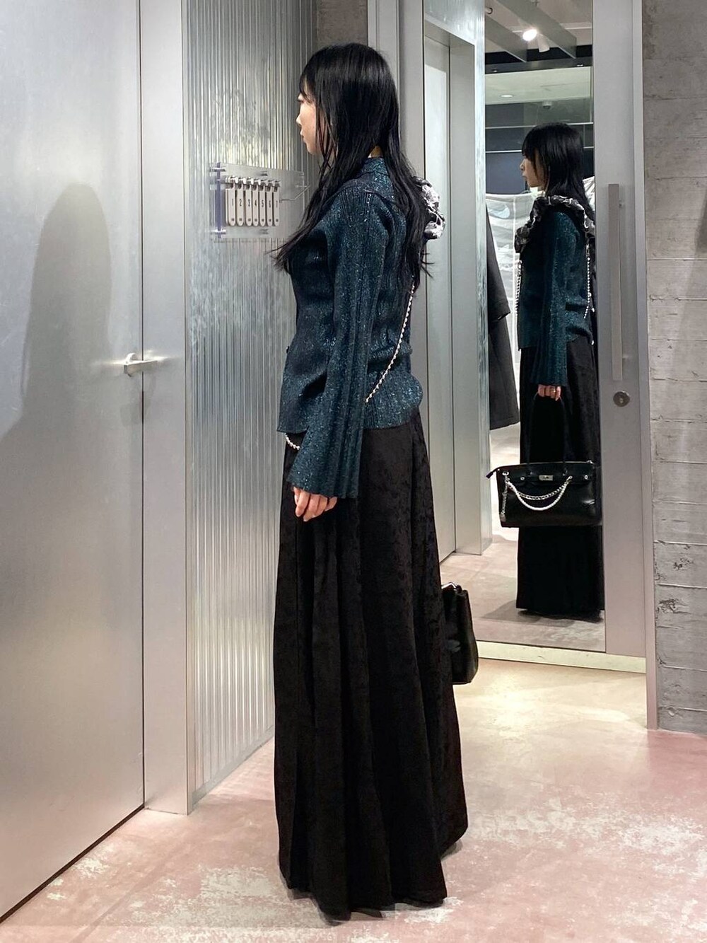 ブラック系のブーツ、ブラック系のボストンバッグ、グリーン系のカーディガン/ボレロを着用したレディースの冬コーディネートの2枚目の写真