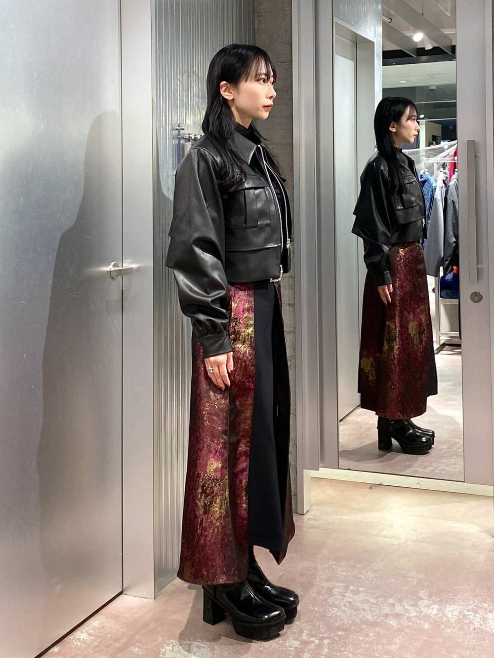 パープル系のスカート、ブラック系のブーツ、ブラック系のブルゾンを着用したレディースの秋コーディネートの4枚目の写真