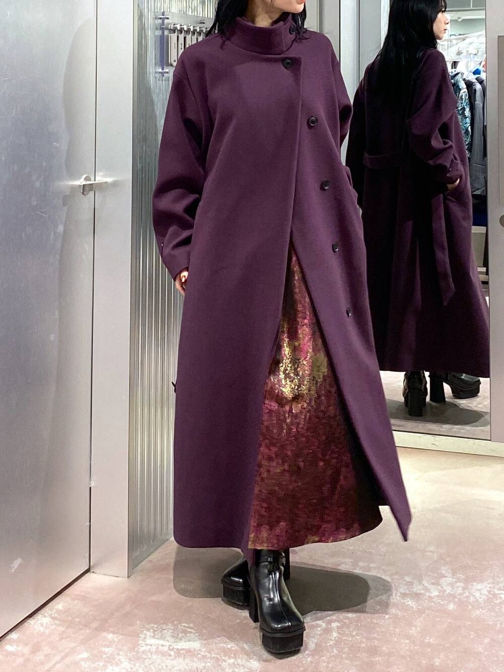 パープル系のチェスターコート、ブラック系のブーツ、パープル系のスカートを着用したレディースの冬コーディネートの5枚目の写真