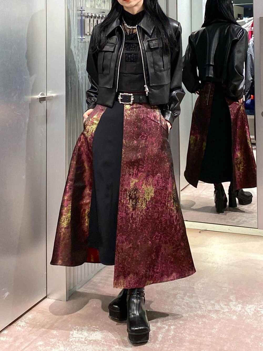 パープル系のスカート、ブラック系のブーツ、ブラック系のブルゾンを着用したレディースの秋コーディネートの5枚目の写真