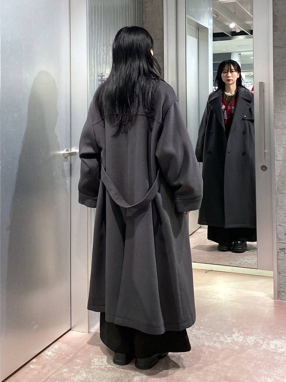 グレー系のトレンチコート、レッド系のカーディガン/ボレロ、イエロー系のTシャツ/カットソーを着用したレディースの冬コーディネートの3枚目の写真