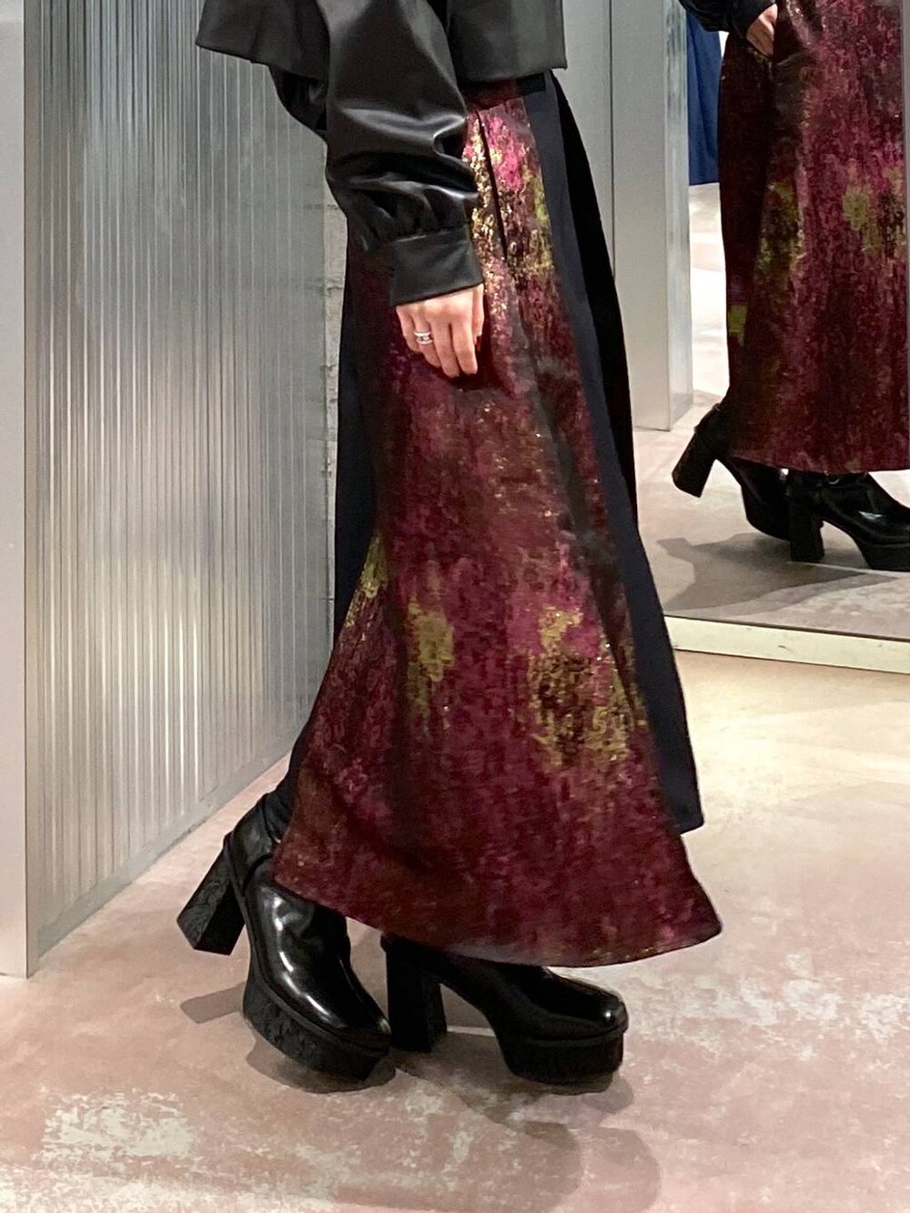 パープル系のスカート、ブラック系のブーツ、ブラック系のブルゾンを着用したレディースの秋コーディネートの6枚目の写真