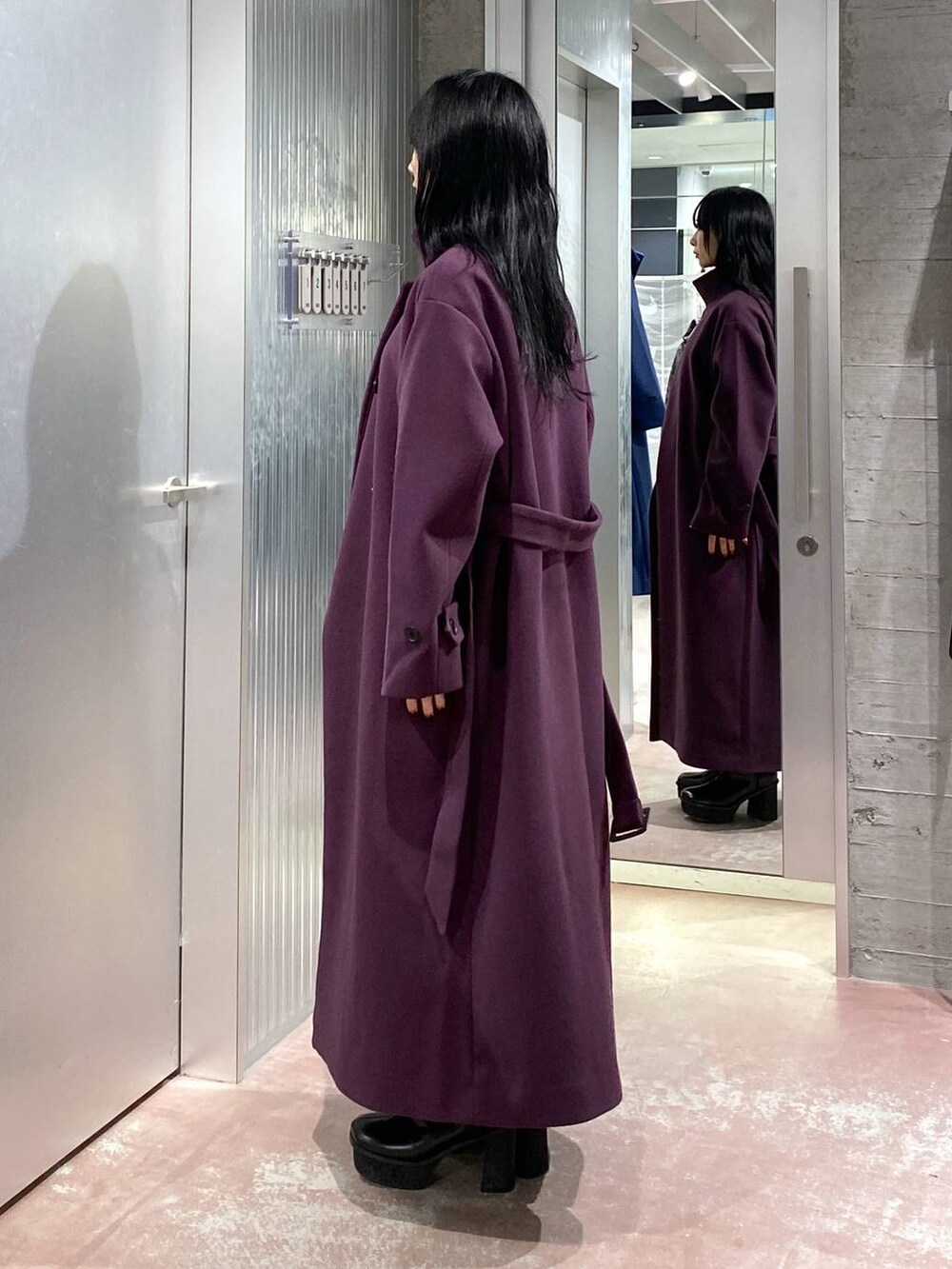 パープル系のチェスターコート、ブラック系のブーツ、パープル系のスカートを着用したレディースの冬コーディネートの2枚目の写真