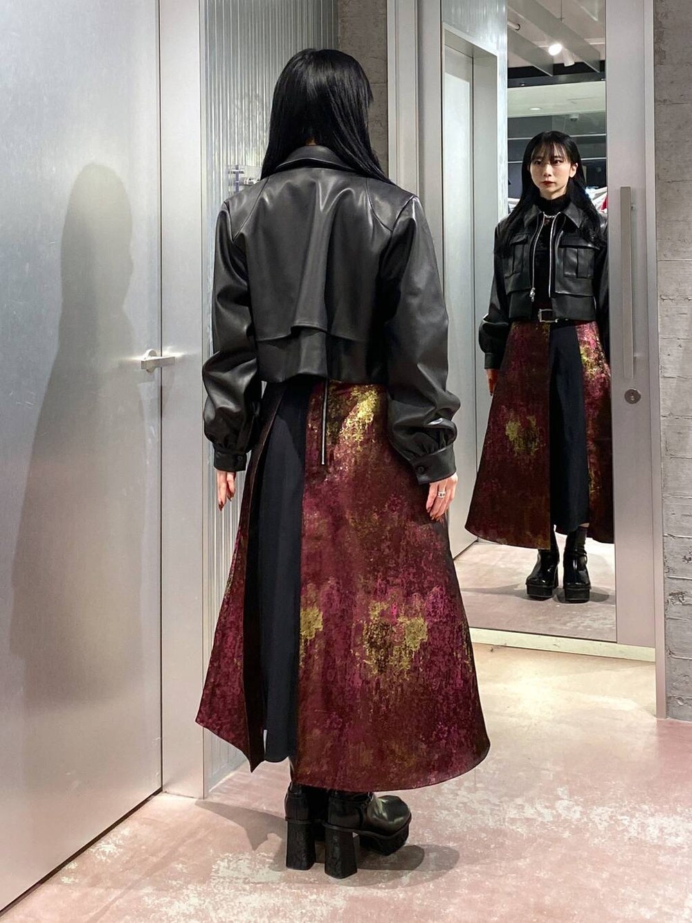 パープル系のスカート、ブラック系のブーツ、ブラック系のブルゾンを着用したレディースの秋コーディネートの3枚目の写真