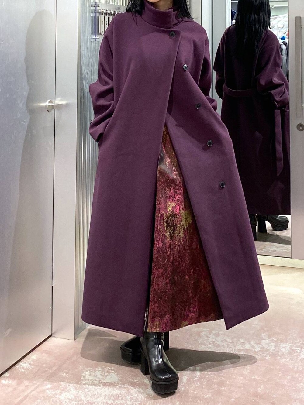 パープル系のチェスターコート、ブラック系のブーツ、パープル系のスカートを着用したレディースの冬コーディネートの8枚目の写真