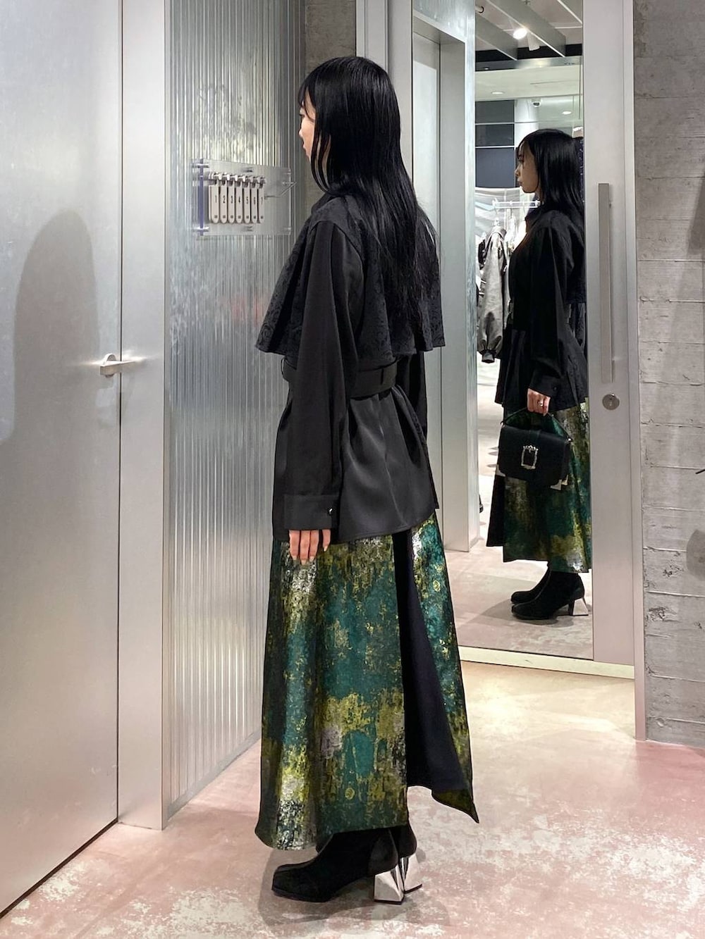 ブラック系のブーツ、イエロー系のスカート、ブラック系のショルダーバッグを着用したレディースの冬コーディネートの2枚目の写真