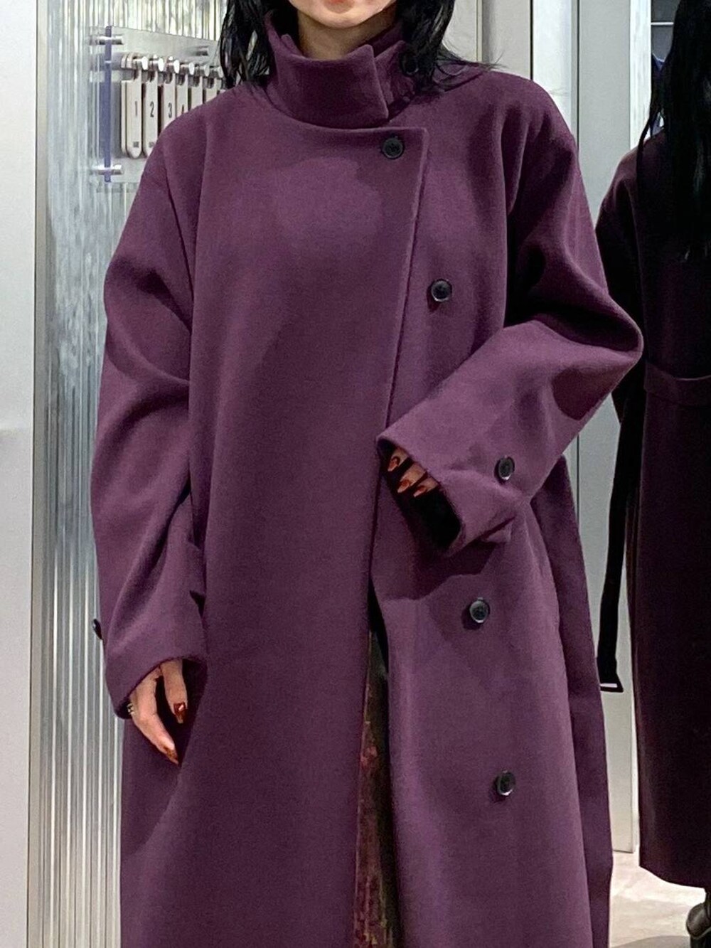 パープル系のチェスターコート、ブラック系のブーツ、パープル系のスカートを着用したレディースの冬コーディネートの6枚目の写真