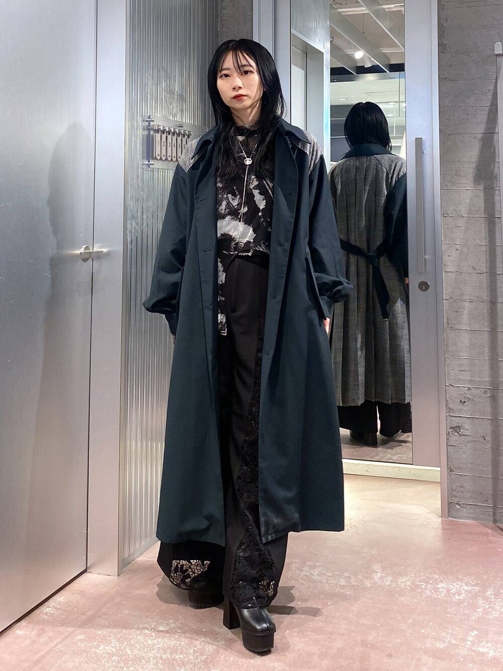 ブラック系のブーツ、グリーン系のステンカラーコート、ブラック系のTシャツ/カットソーを着用したレディースの秋コーディネートの2枚目の写真