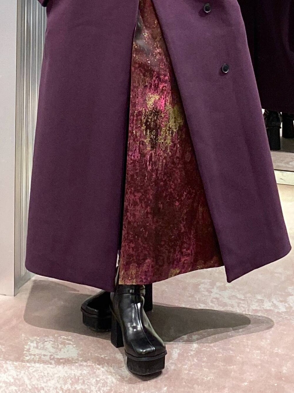 パープル系のチェスターコート、ブラック系のブーツ、パープル系のスカートを着用したレディースの冬コーディネートの9枚目の写真