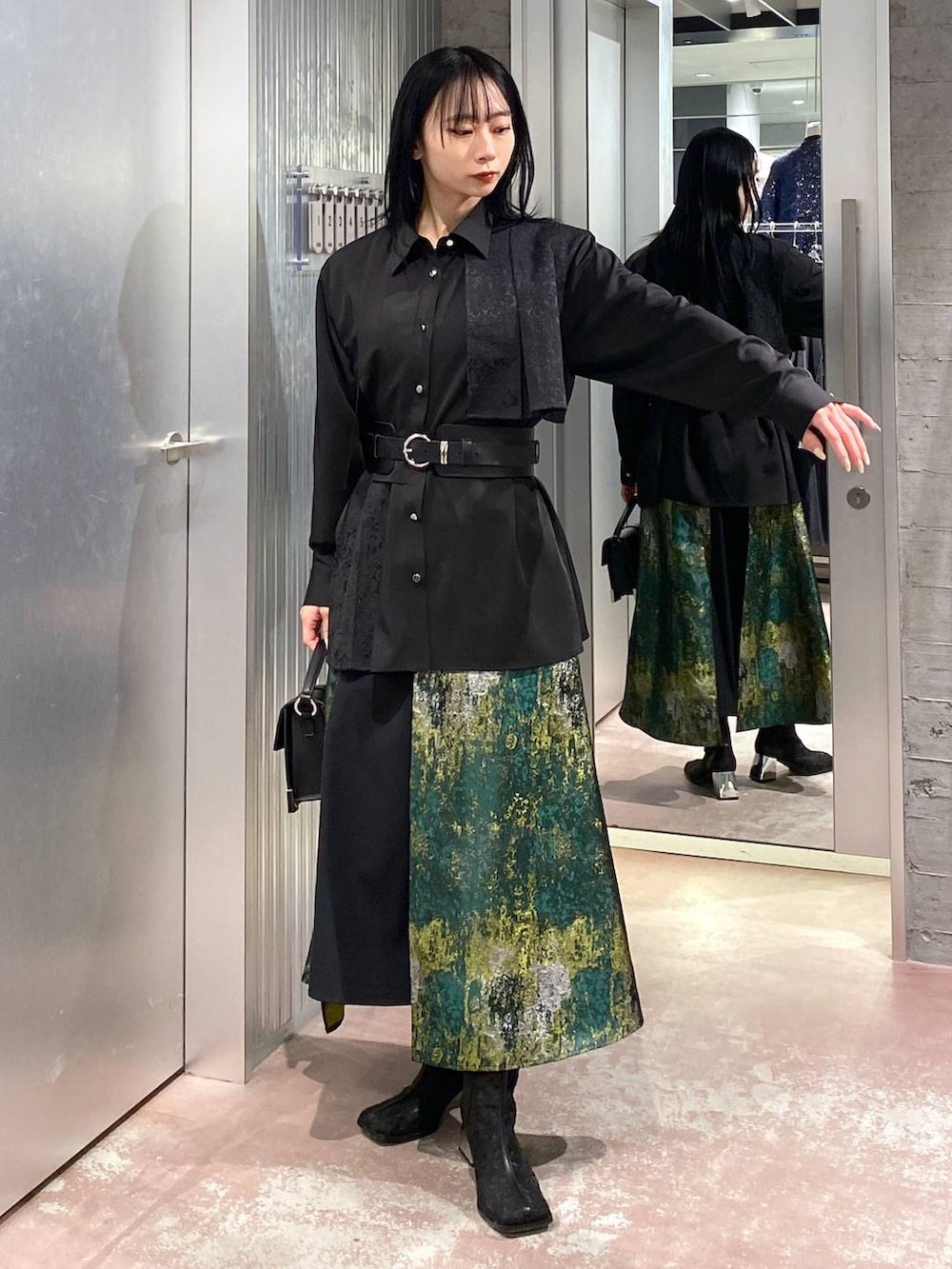 ブラック系のブーツ、イエロー系のスカート、ブラック系のショルダーバッグを着用したレディースの冬コーディネートの5枚目の写真