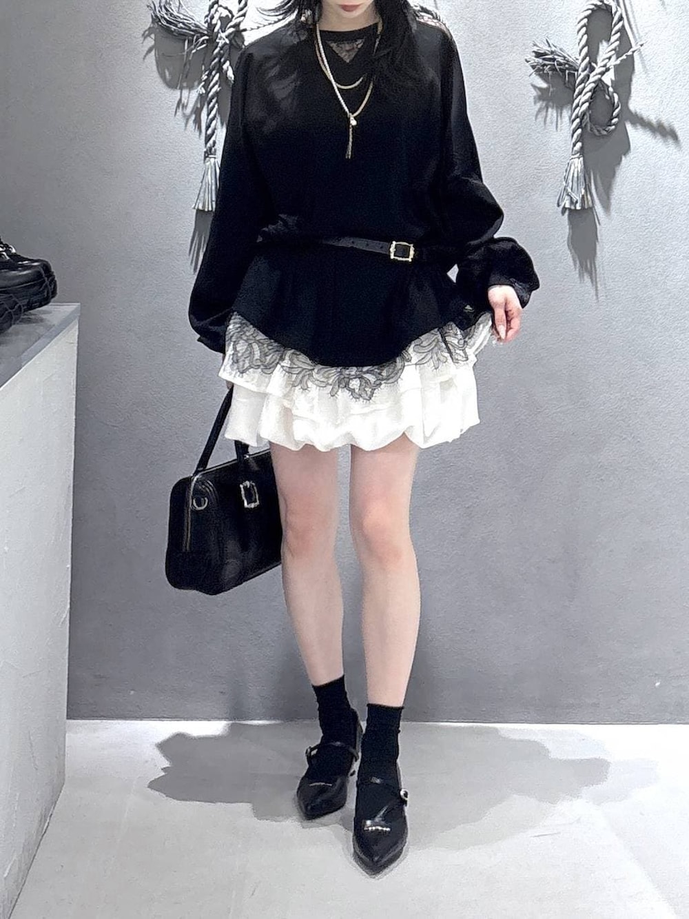 ブラック系のボストンバッグ、ブラック系のパンプス、ホワイト系のスカートを着用したレディースの冬コーディネートの5枚目の写真