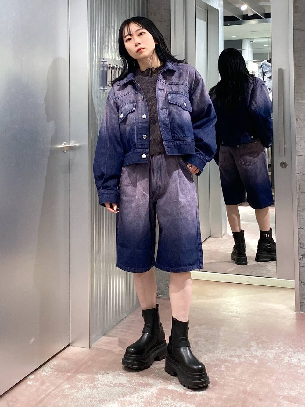 グレー系のニット/セーター、ブラック系のブーツ、パープル系のデニムジャケットを着用したレディースの冬コーディネートの2枚目の写真