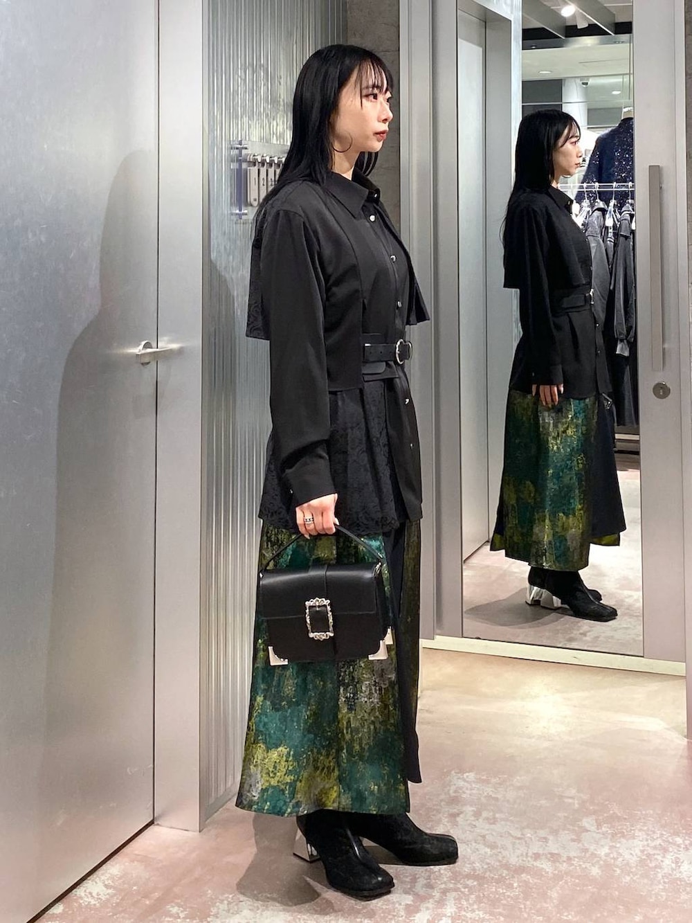 ブラック系のブーツ、イエロー系のスカート、ブラック系のショルダーバッグを着用したレディースの冬コーディネートの4枚目の写真