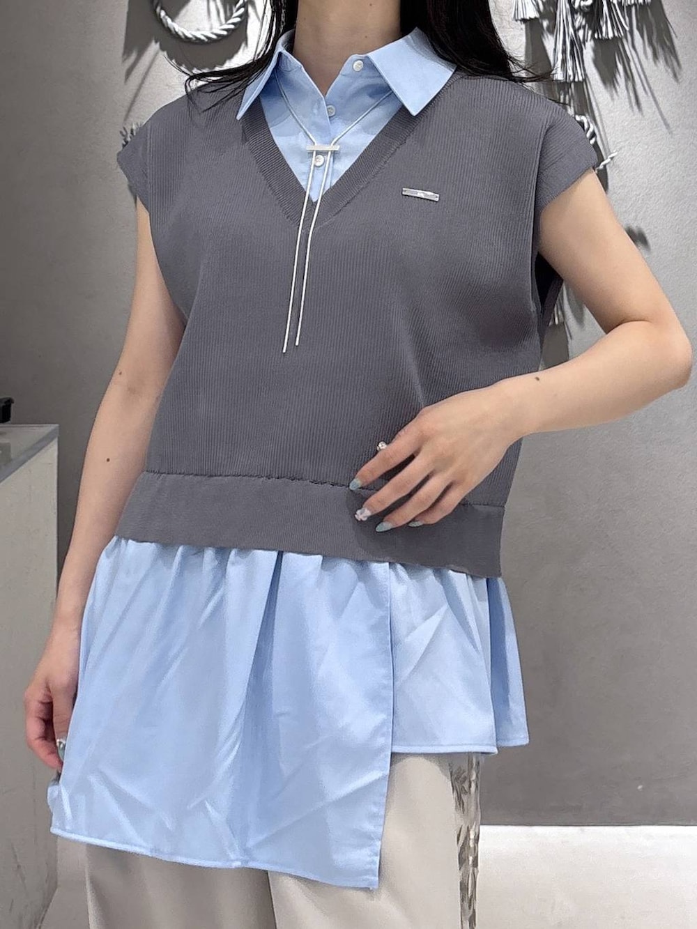 ブルー系のベスト、ホワイト系のスラックス、ブラック系のサンダルを着用したレディースの夏コーディネートの6枚目の写真