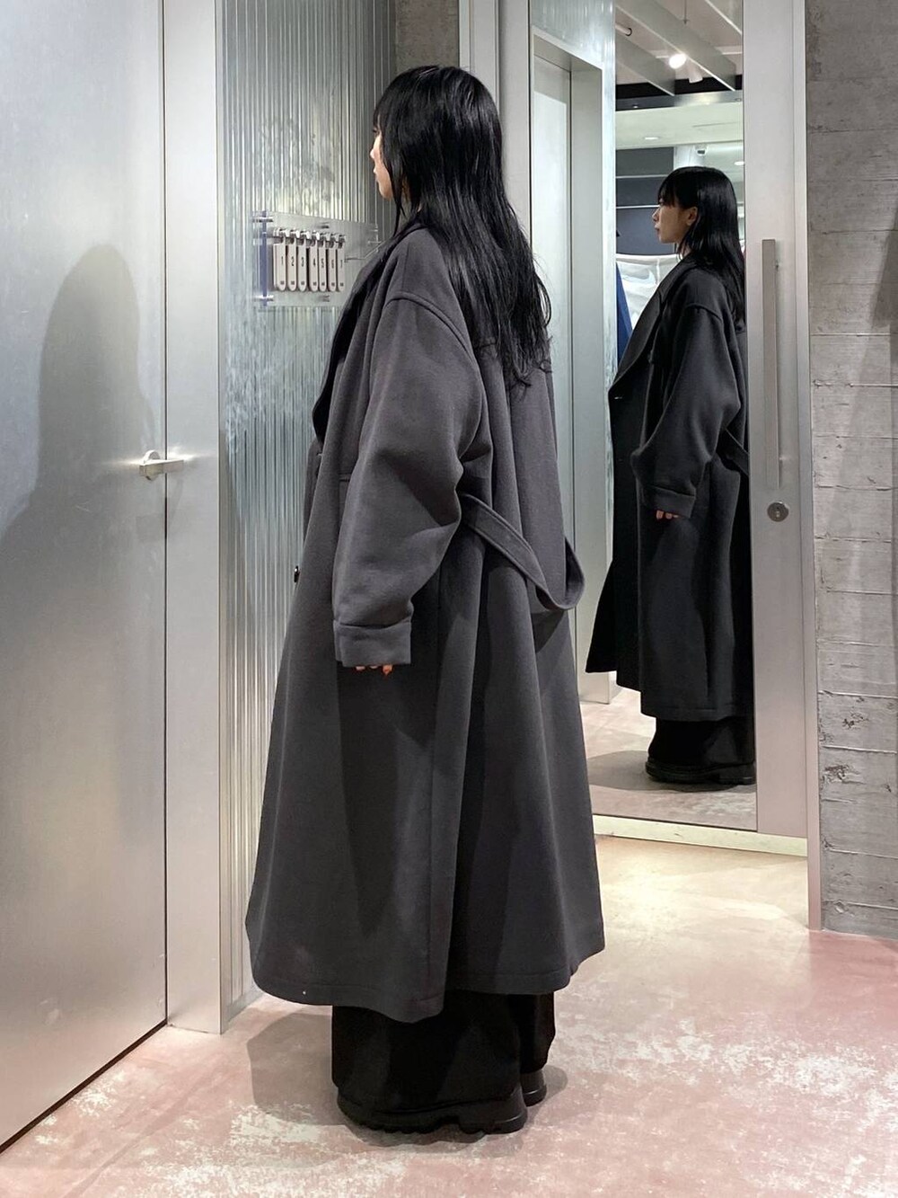 グレー系のトレンチコート、レッド系のカーディガン/ボレロ、イエロー系のTシャツ/カットソーを着用したレディースの冬コーディネートの2枚目の写真