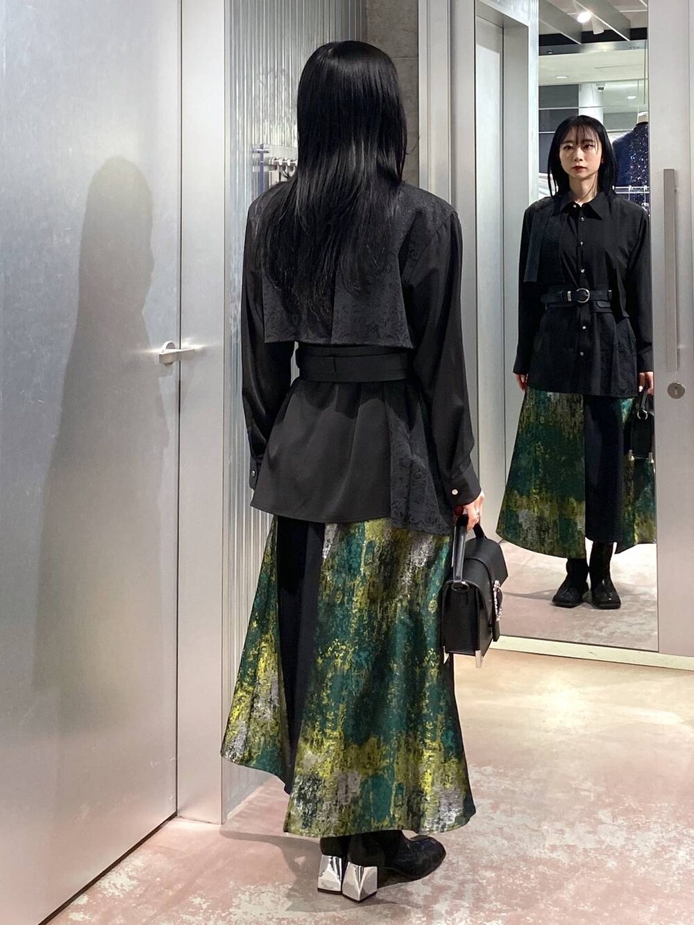 ブラック系のブーツ、イエロー系のスカート、ブラック系のショルダーバッグを着用したレディースの冬コーディネートの3枚目の写真