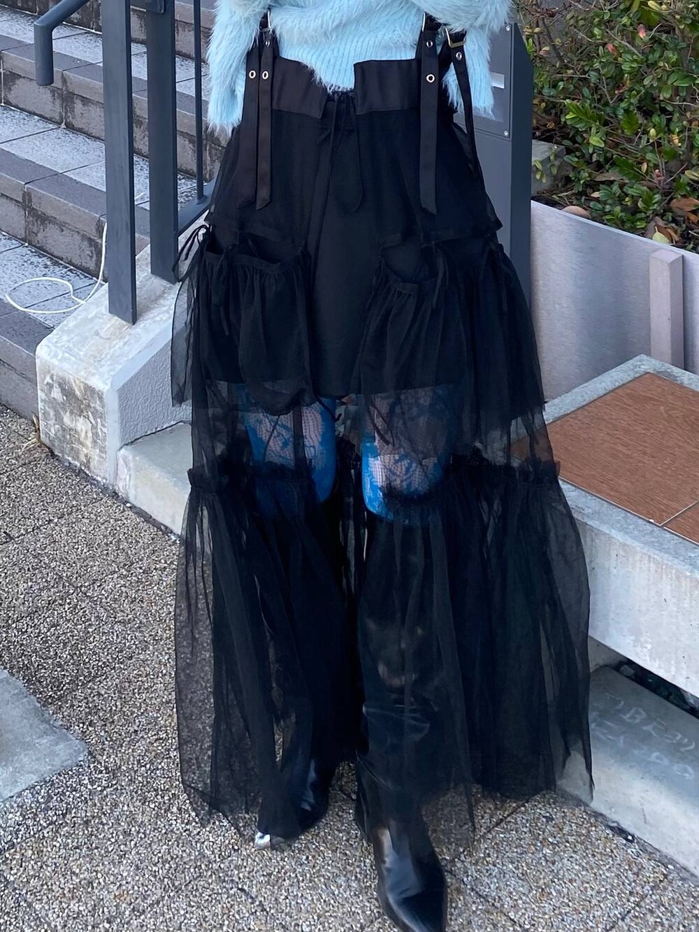 グリーン系のニット/セーター、ブラック系のスカート、ブラック系のブーツを着用したレディースの冬コーディネートの2枚目の写真