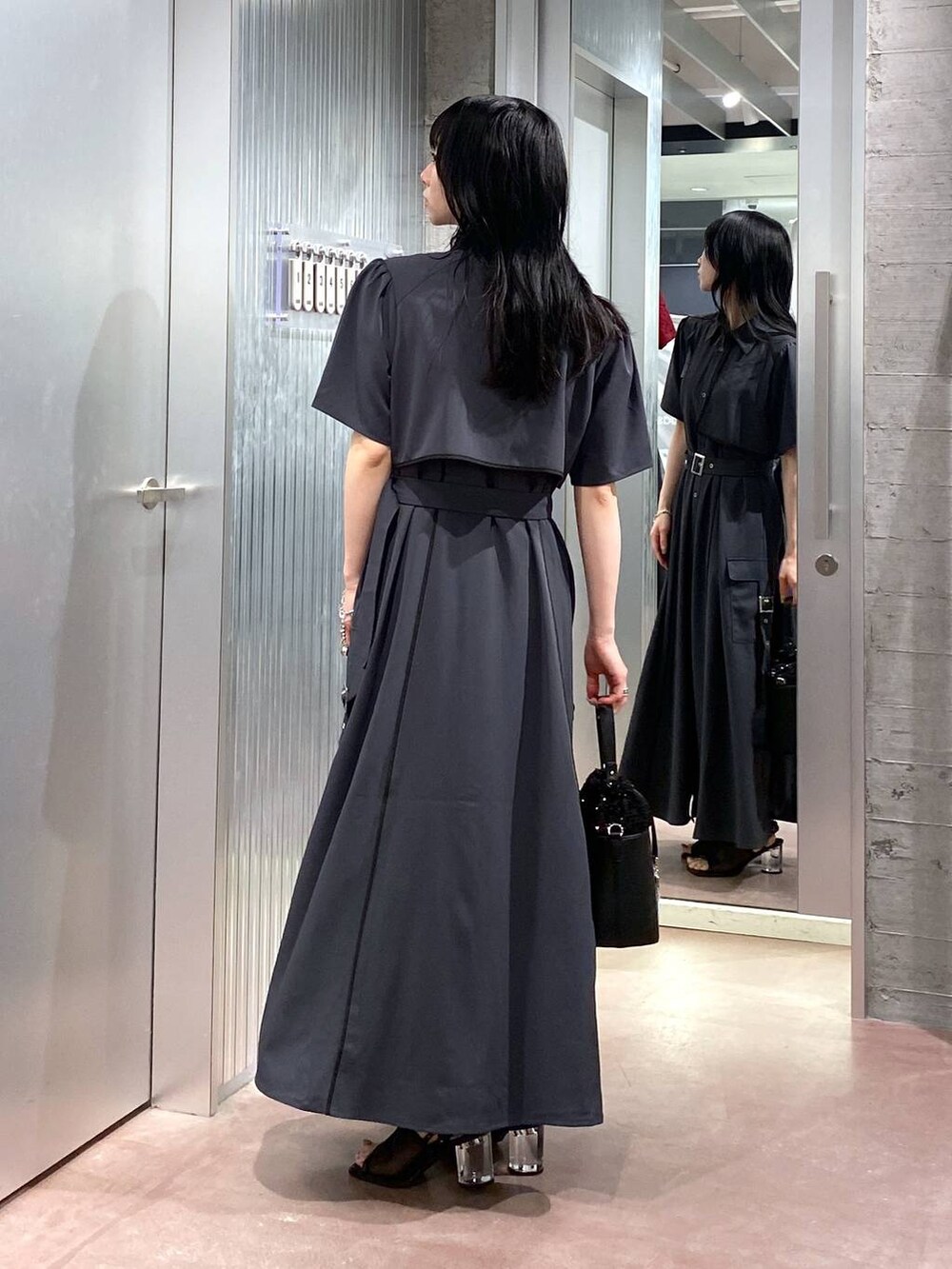 ブラック系のサンダル、グレー系のワンピース、ブラック系のショルダーバッグを着用したレディースの夏コーディネートの2枚目の写真