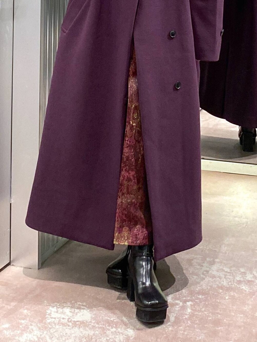 パープル系のチェスターコート、ブラック系のブーツ、パープル系のスカートを着用したレディースの冬コーディネートの7枚目の写真