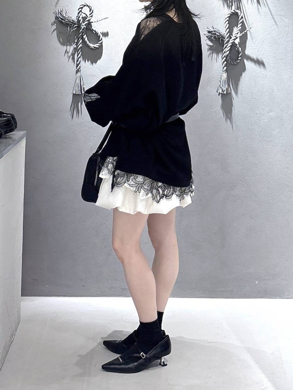 ブラック系のボストンバッグ、ブラック系のパンプス、ホワイト系のスカートを着用したレディースの冬コーディネートの2枚目の写真