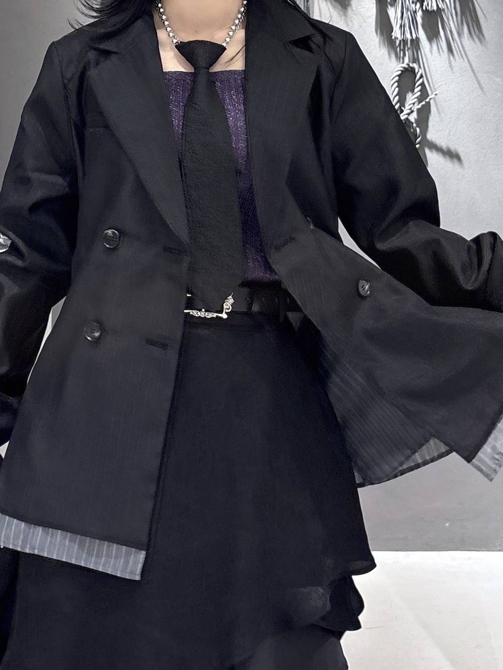 ブラック系のネクタイ、ブラック系のブーツ、パープル系のタンクトップを着用したレディースの春コーディネートの8枚目の写真