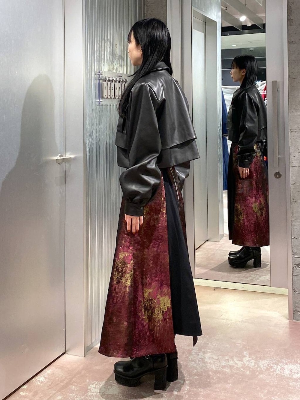 パープル系のスカート、ブラック系のブーツ、ブラック系のブルゾンを着用したレディースの秋コーディネートの2枚目の写真