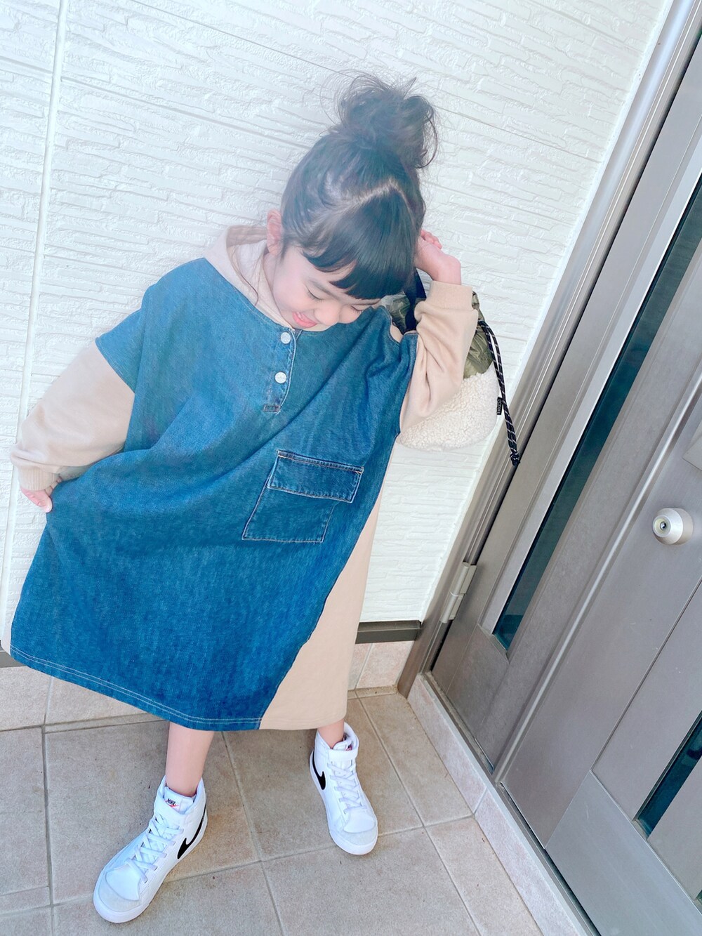 ベージュ系のワンピース、グリーン系のバッグ、ホワイト系のスニーカーを着用したキッズの冬コーディネートの2枚目の写真