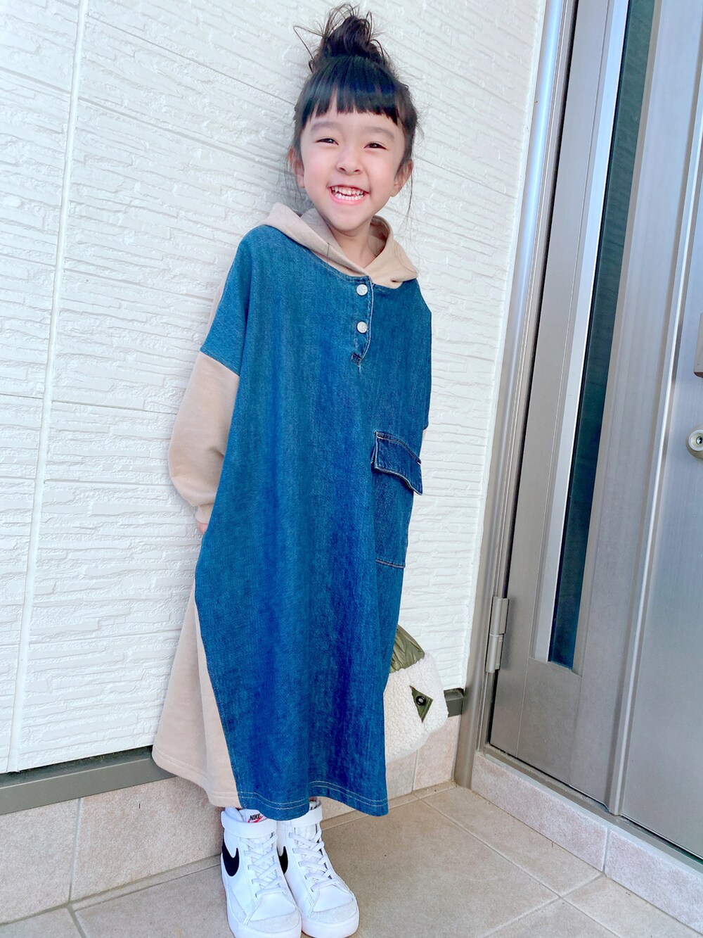 ベージュ系のワンピース、グリーン系のバッグ、ホワイト系のスニーカーを着用したキッズの冬コーディネートの4枚目の写真