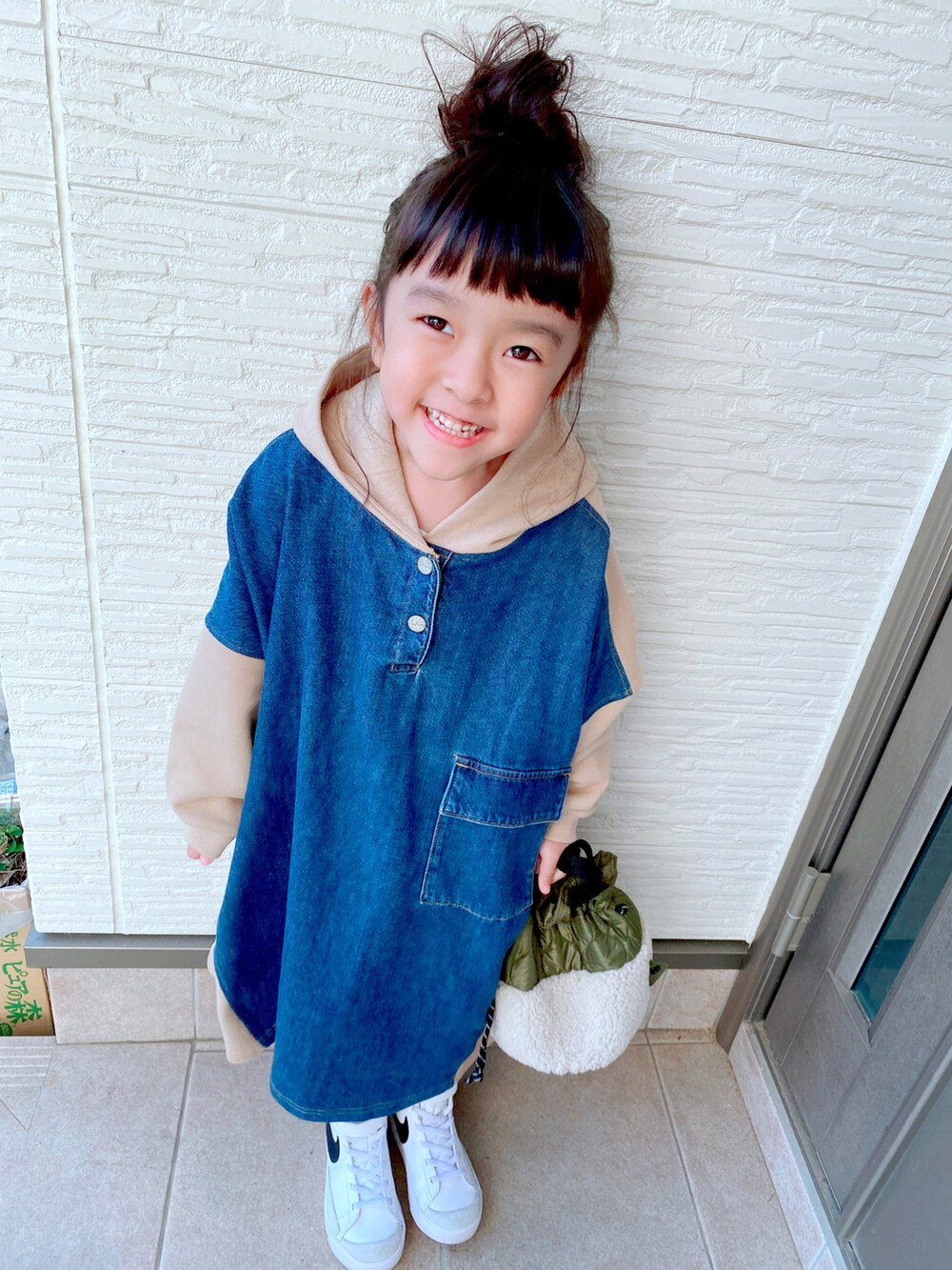 ベージュ系のワンピース、グリーン系のバッグ、ホワイト系のスニーカーを着用したキッズの冬コーディネートの3枚目の写真