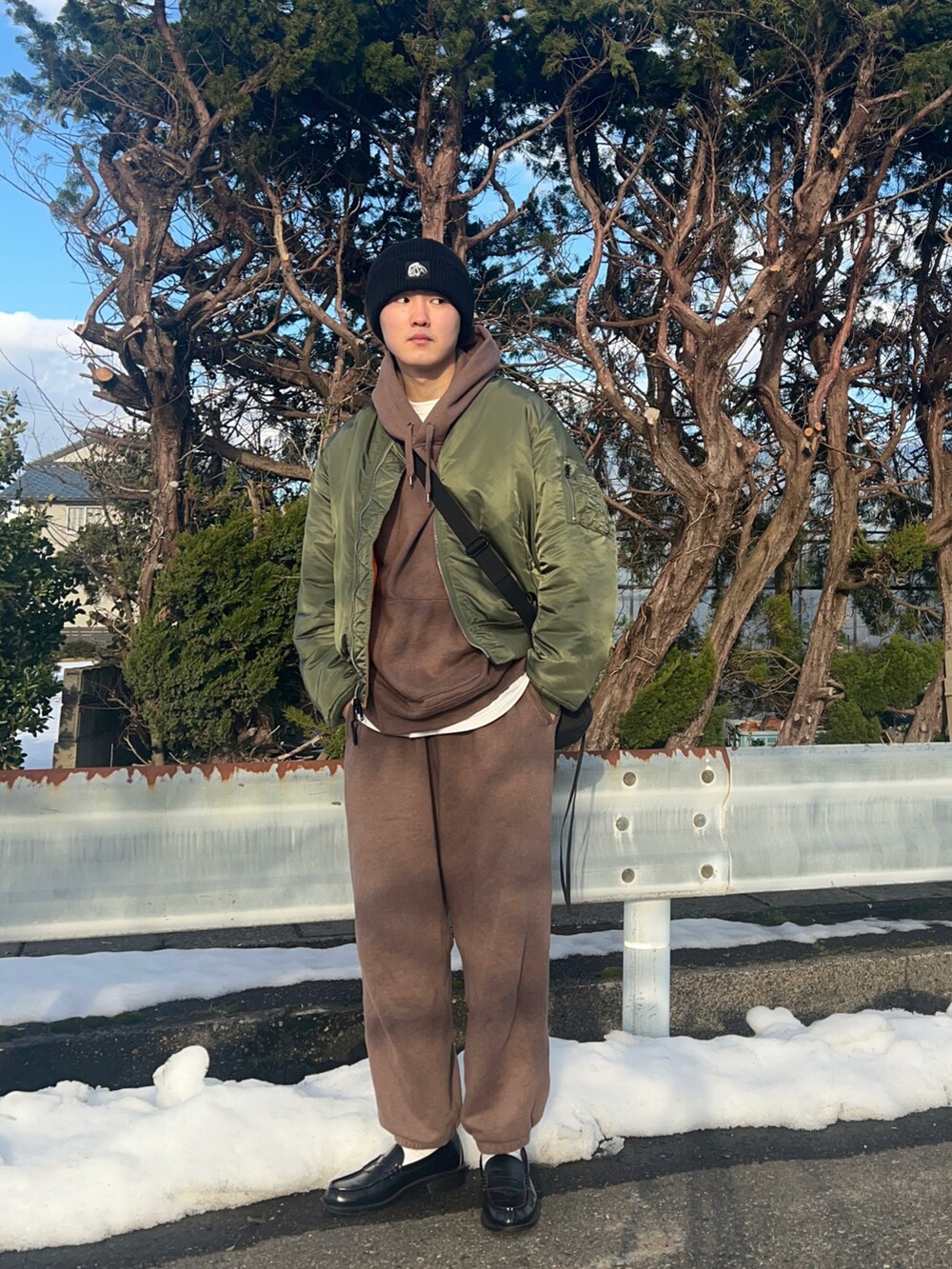 グリーン系のMA-1、ブラウン系のパーカー、ホワイト系のTシャツ/カットソーを着用したメンズの冬コーディネートの2枚目の写真