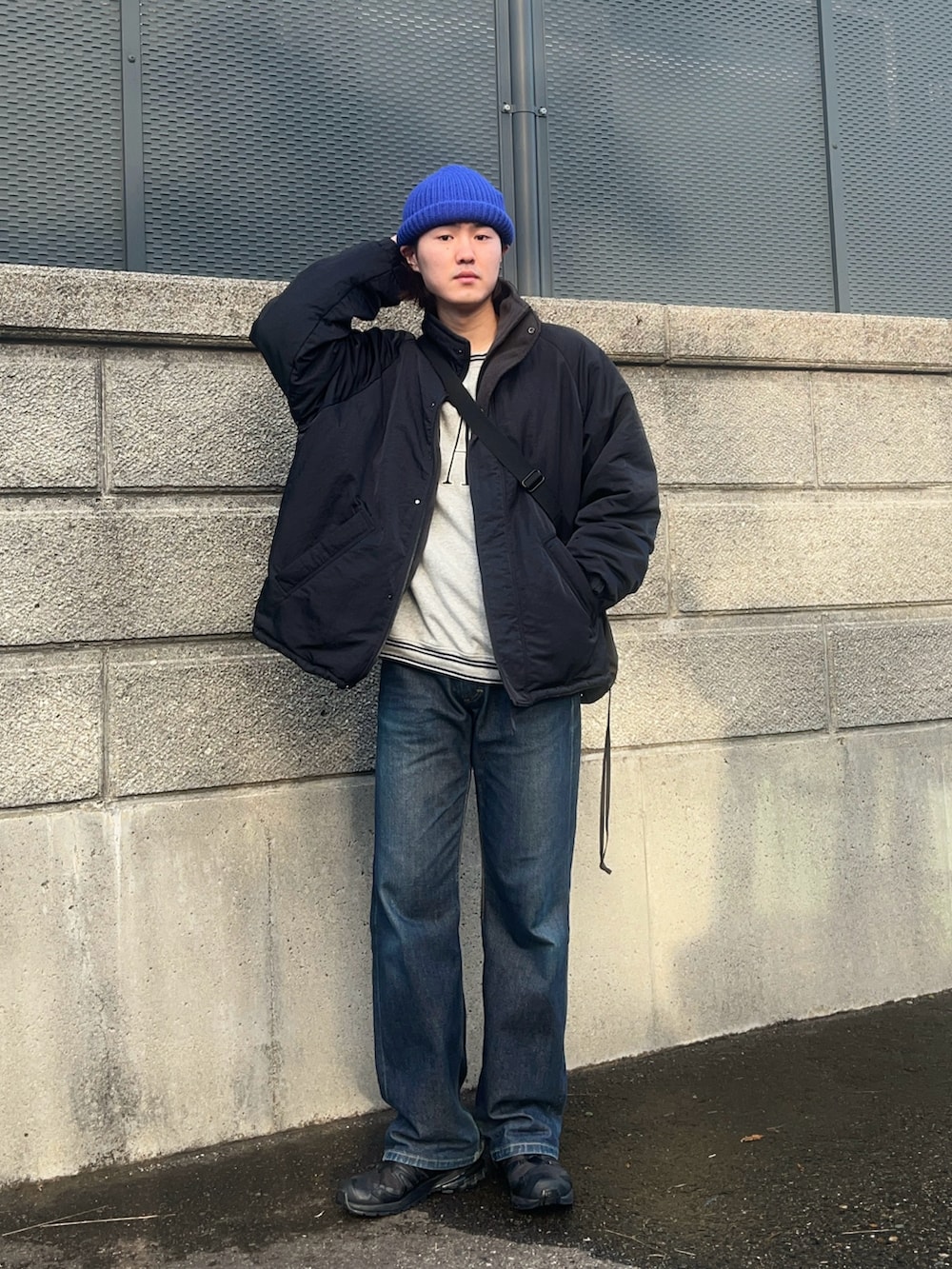 ブラック系のブルゾン、グレー系のスウェット、ブルー系のデニムパンツを着用したメンズの冬コーディネートの2枚目の写真