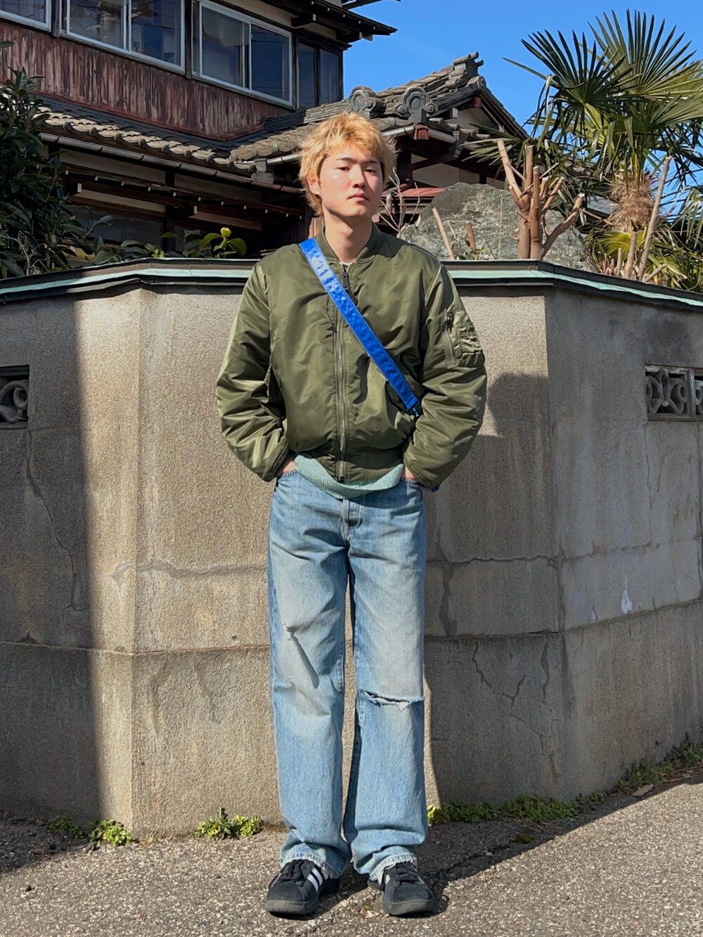 グリーン系のMA-1、グリーン系のニット/セーター、ブルー系のデニムパンツを着用したメンズの春コーディネートの2枚目の写真