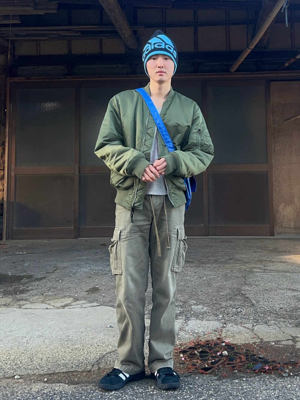 グリーン系のMA-1、グレー系のニット/セーター、グリーン系のカーゴパンツを着用したメンズの春コーディネートの2枚目の写真