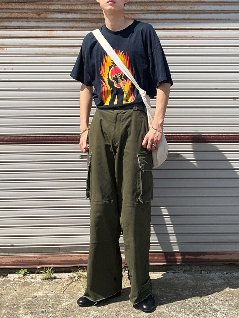 ブラック系のTシャツ/カットソー、グリーン系のカーゴパンツ、ブラック系のドレスシューズを着用したメンズの夏コーディネートの2枚目の写真