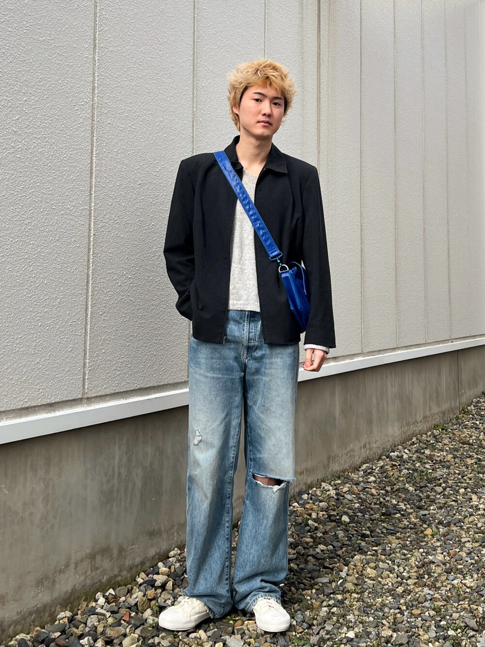 ブラック系のジャケット/アウター、グレー系のニット/セーター、ブルー系のデニムパンツを着用したメンズの春コーディネートの2枚目の写真