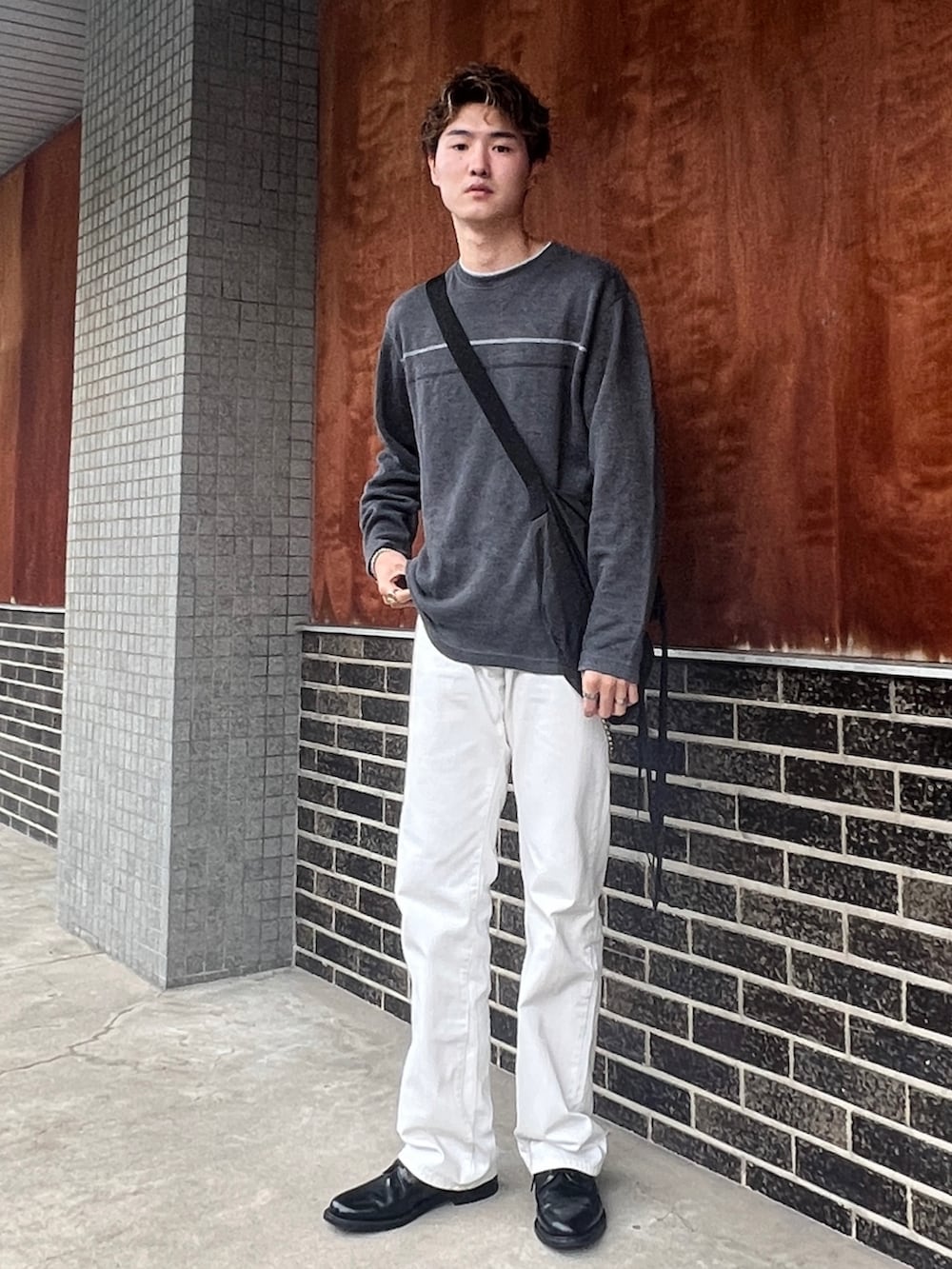 グレー系のニット/セーター、ホワイト系のパンツ、ブラック系のドレスシューズを着用したメンズの秋コーディネートの2枚目の写真