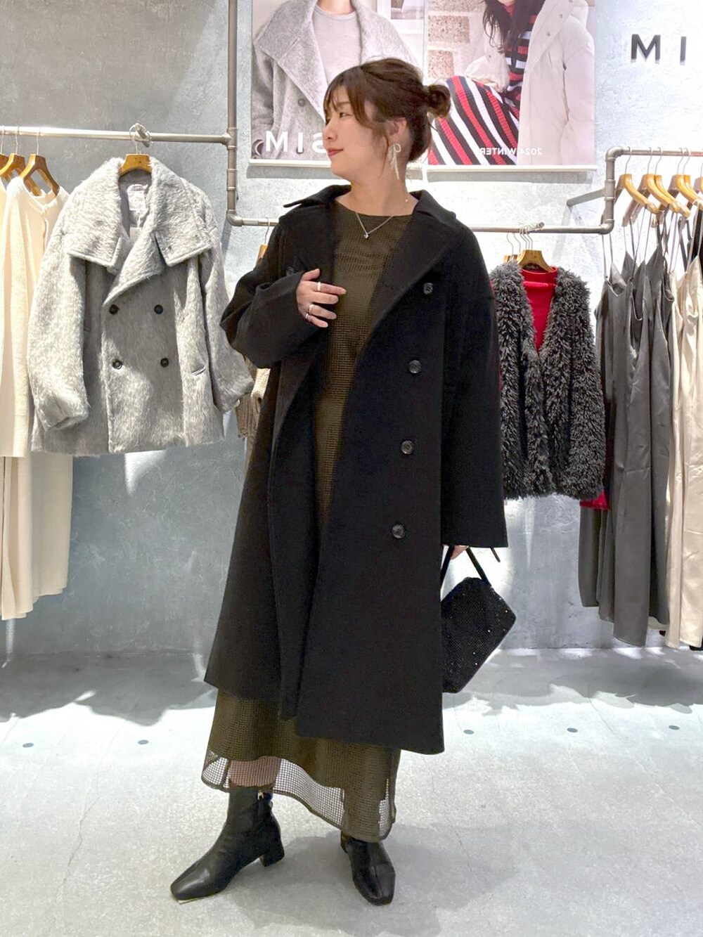 ブラック系のその他アウター、ブラック系のブーツ、グリーン系のドレスを着用したレディースの秋コーディネートの5枚目の写真