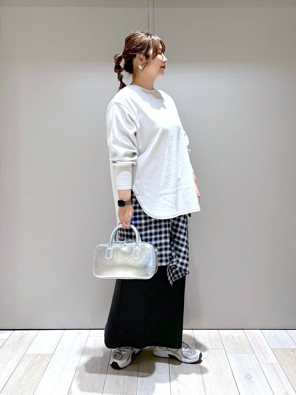 ベージュ系のTシャツ/カットソー、シルバー系のボストンバッグ、ブラック系のスカートを着用したレディースの秋コーディネートの2枚目の写真