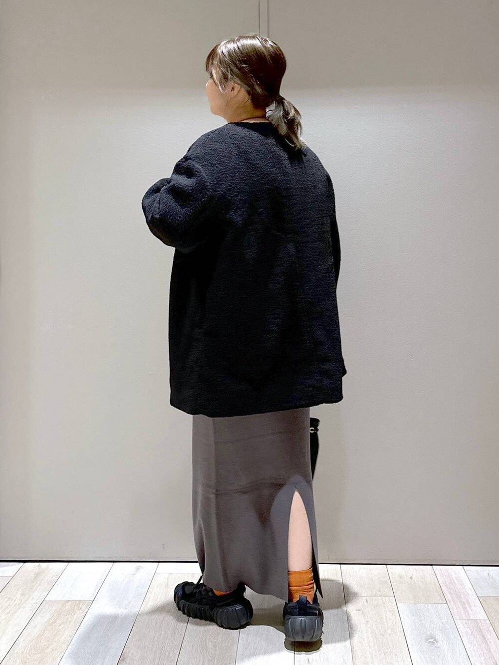 グレー系のスカート、ブラック系のノーカラーコート、ホワイト系のワンピースを着用したレディースの秋コーディネートの3枚目の写真