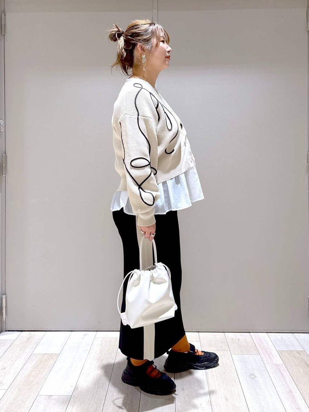 ホワイト系のTシャツ/カットソー、ブラック系のスニーカー、ブラック系のスカートを着用したレディースの春コーディネートの2枚目の写真