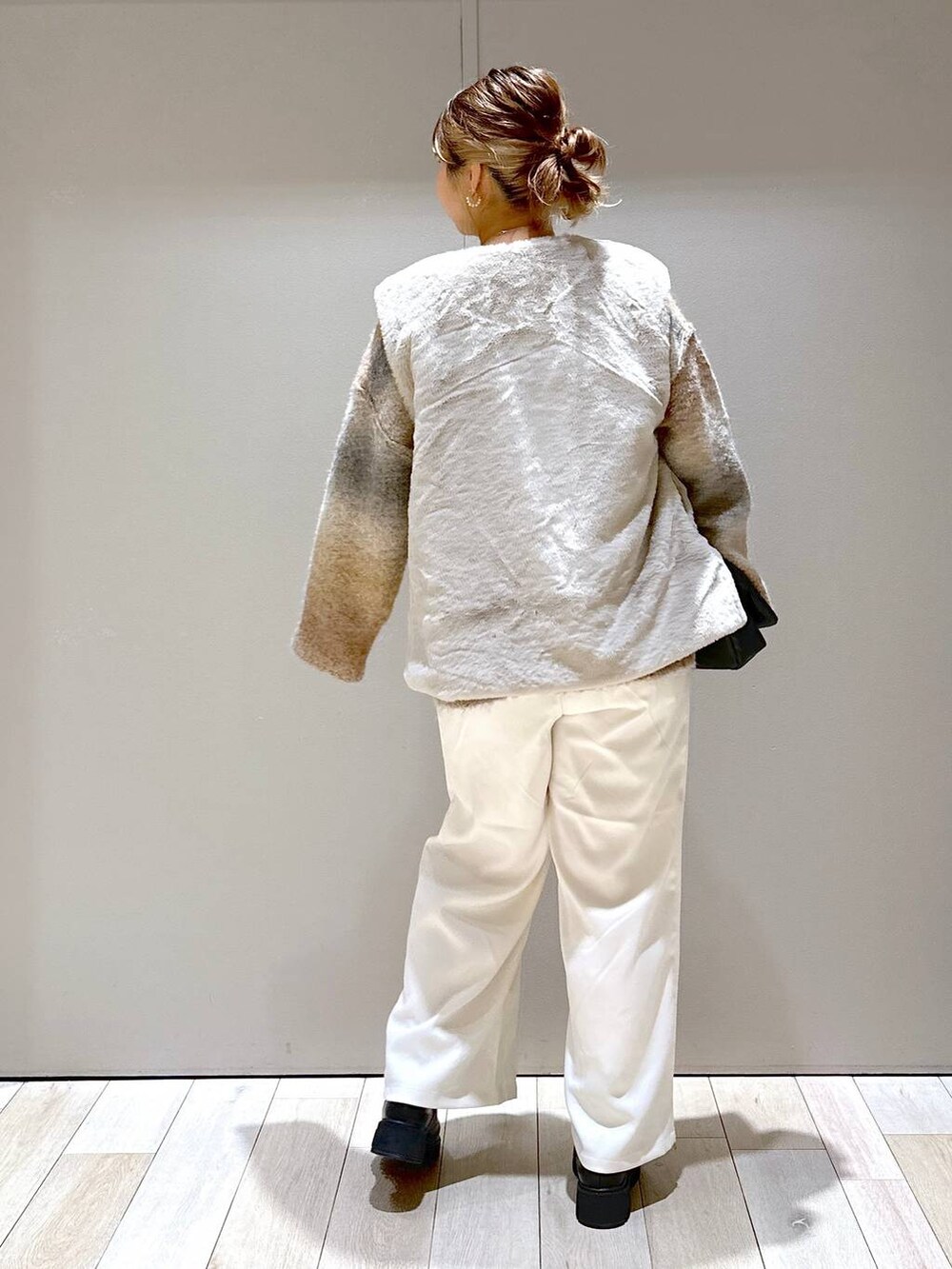 ホワイト系のモッズコート、ブラック系のブーツ、ブラック系のショルダーバッグを着用したレディースの秋コーディネートの3枚目の写真