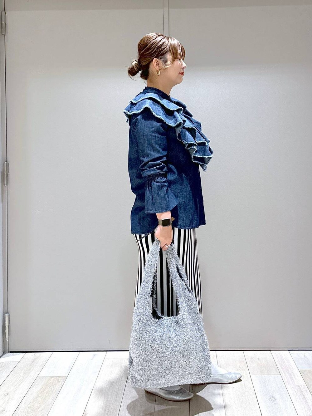 シルバー系のショルダーバッグ、シルバー系のパンプス、ブラック系のスカートを着用したレディースの秋コーディネートの2枚目の写真