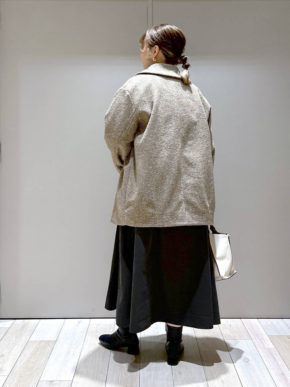 ブラウン系のチェスターコート、ベージュ系のショルダーバッグ、ブラック系のブーツを着用したレディースの秋コーディネートの3枚目の写真