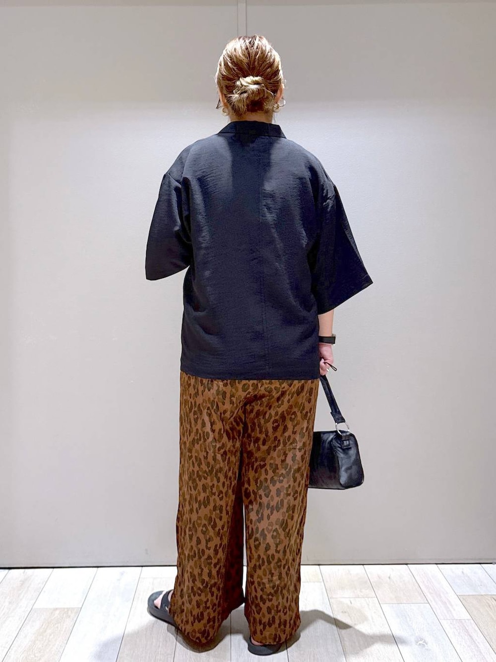 ブラック系のテーラードジャケット、ブラック系のサンダル、ブラック系のハンドバッグを着用したレディースの夏コーディネートの3枚目の写真