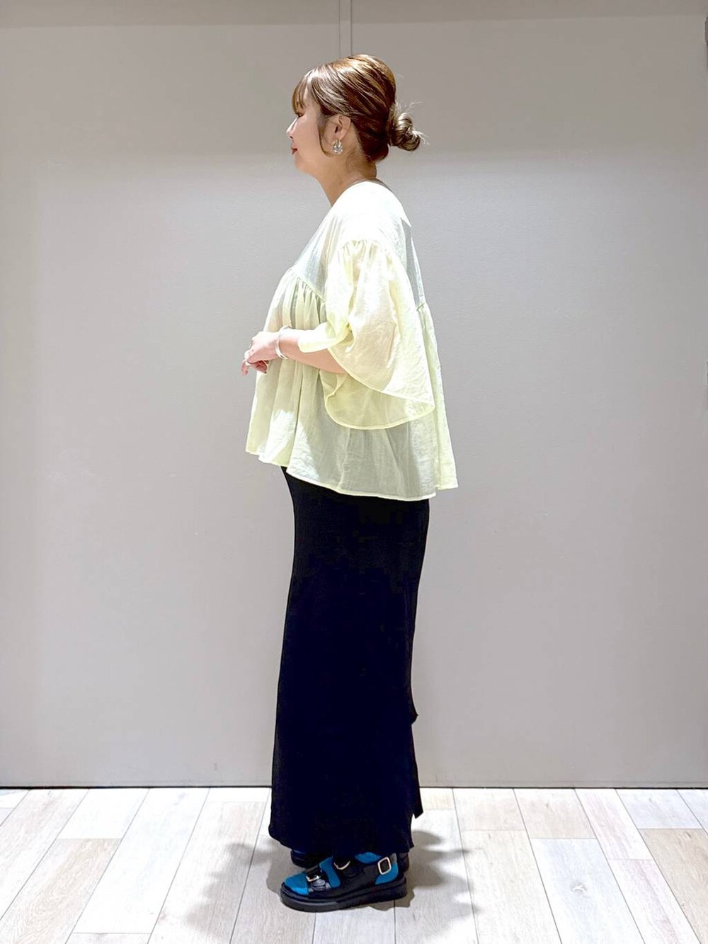 ブラック系のスカート、イエロー系のシャツ/ブラウス、ブラック系のサンダルを着用したレディースの夏コーディネートの4枚目の写真