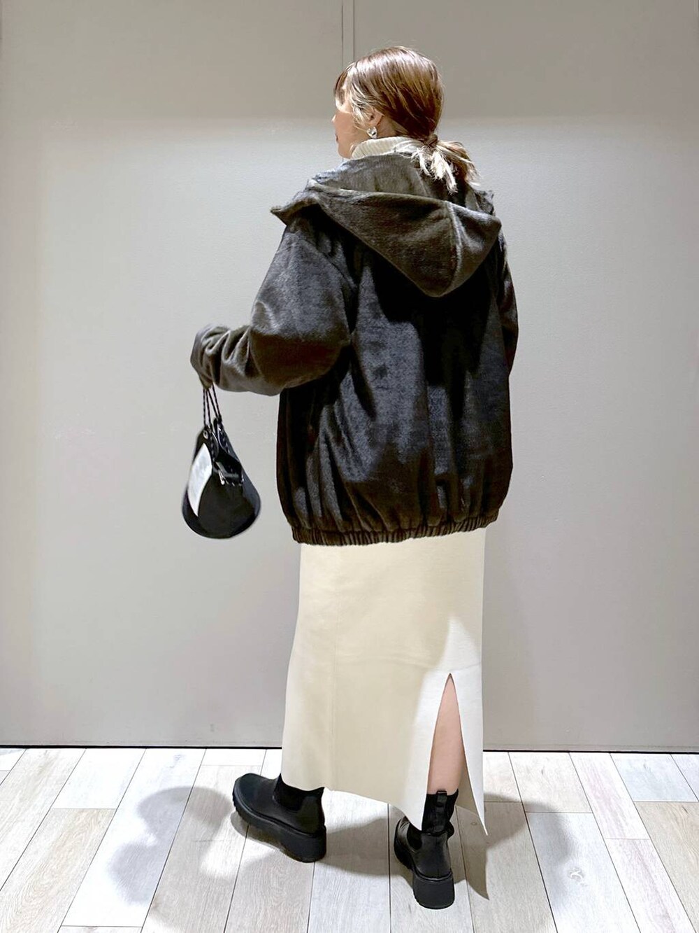 ホワイト系のニット/セーター、ホワイト系のスカート、グリーン系のブルゾンを着用したレディースの冬コーディネートの4枚目の写真