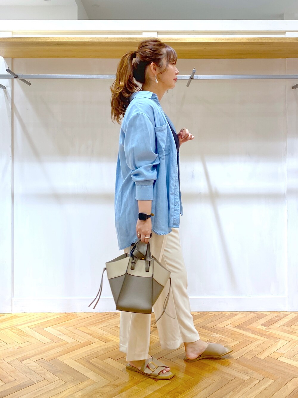 ブルー系のシャツ/ブラウス、ブラック系のニット/セーター、ホワイト系のスラックスを着用したレディースの夏コーディネートの2枚目の写真